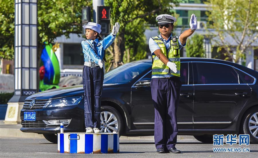 9月6日,在文安县商业街十字路口"小交警"在交警的指导下指挥交通.