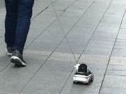 Looking at a man dragging a toy car, I initially thought he was bored and idle, but upon closer inspection: What a cute little guy!
