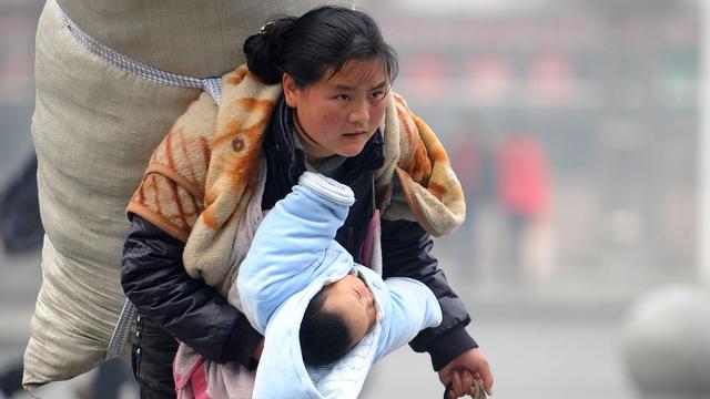 一位母亲背着行囊带着孩子返乡 新华社记者 周科拍下了这张感人照片