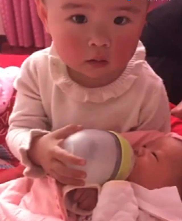 一岁半姐姐给弟弟喂奶，无奈的深深叹了口气，妈妈一旁忍不住笑了