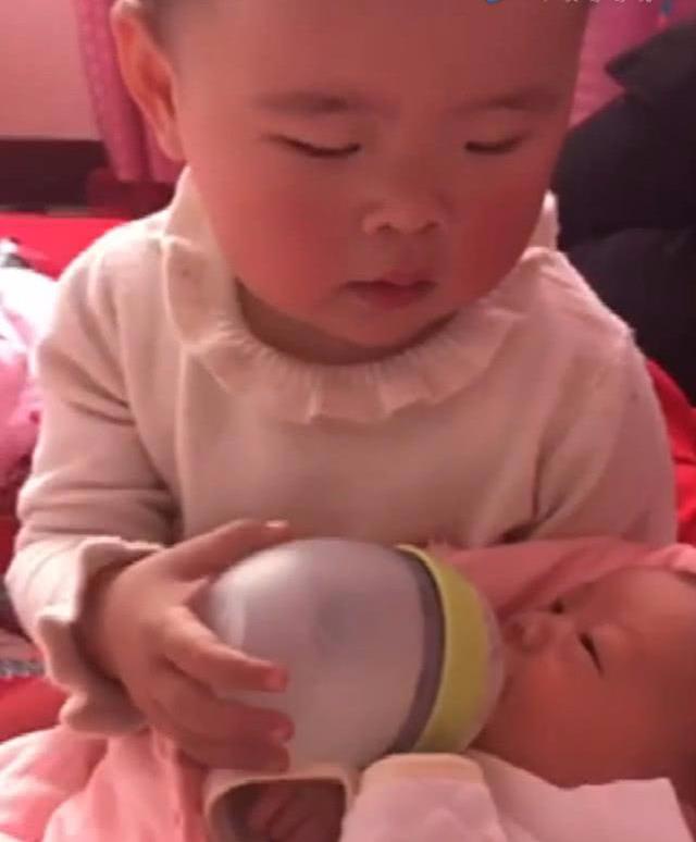 一岁半姐姐给弟弟喂奶，无奈的深深叹了口气，妈妈一旁忍不住笑了