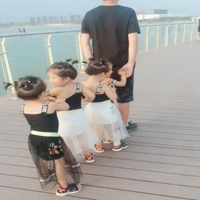 爸爸带四胞胎出去游玩，女儿们的表现太可爱了，让路人羡慕不已