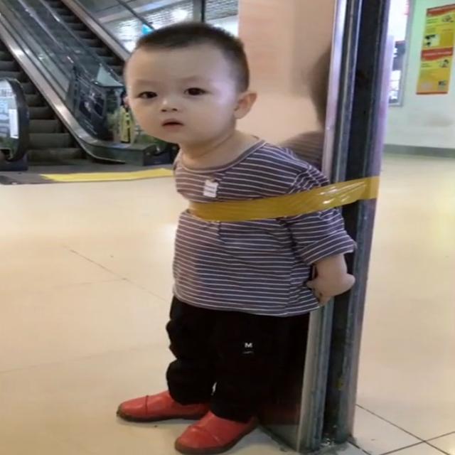 宝宝被绑在柱子上，一脸无奈表情，网友：旁边人的态度让人无语