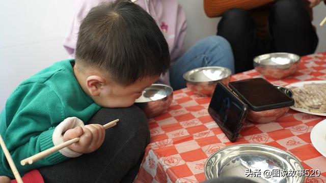 春节饭桌上2岁二胎娃：不吃饭迷“手机”，70岁奶奶用碗搭托架