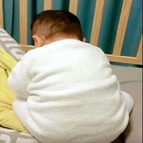 宝宝安安静静坐在小床里，妈妈走过去一看，被宝宝的样子给萌翻了