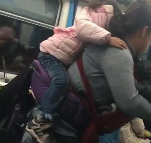 “艰辛妈妈”带两孩子坐火车，背一个抱一个，网友：真是为母则强