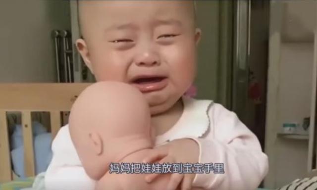 妈妈指着娃娃对宝宝说：“这是你弟弟”，宝宝表现让人好笑又心疼