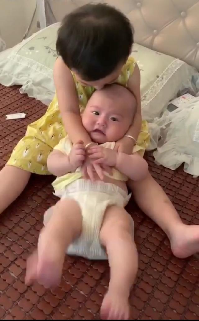 姐姐疼爱弟弟，紧抱着弟弟不让动，弟弟的反应让人哭笑不得