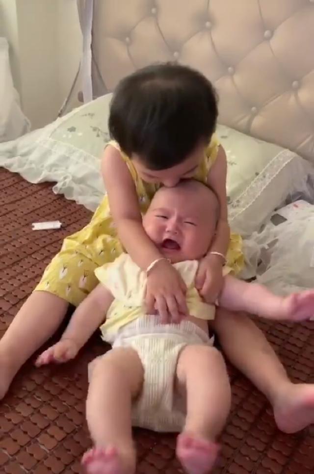 姐姐疼爱弟弟，紧抱着弟弟不让动，弟弟的反应让人哭笑不得