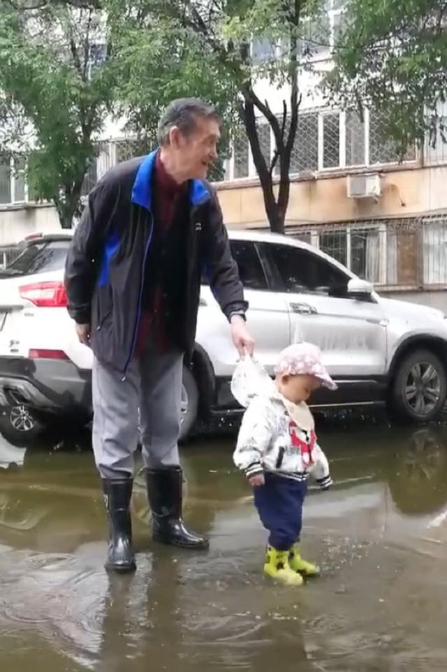 下雨天宝宝想踩水，太爷爷穿起雨靴陪宝宝，看着这画面太温馨了