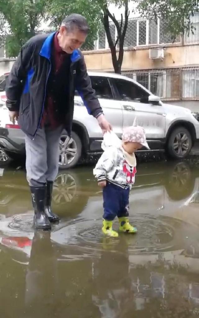 下雨天宝宝想踩水，太爷爷穿起雨靴陪宝宝，看着这画面太温馨了