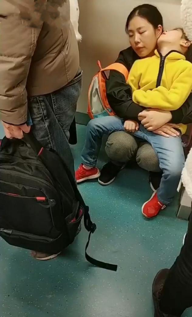 妈妈带熟睡的女儿坐地铁，没人让座蹲在地上，妈妈的表情让人心疼