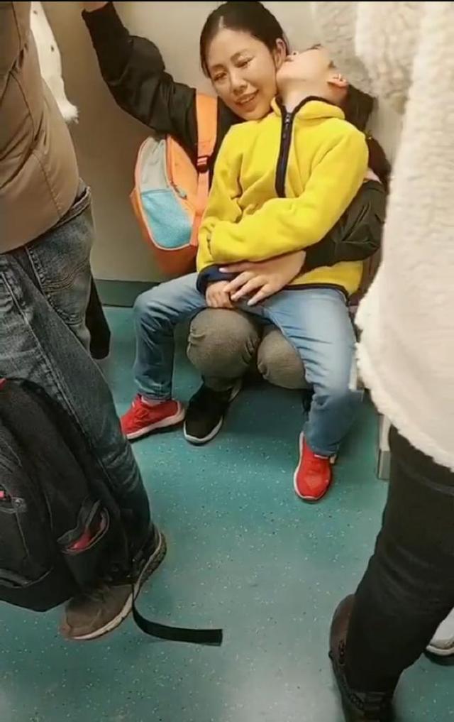 妈妈带熟睡的女儿坐地铁，没人让座蹲在地上，妈妈的表情让人心疼