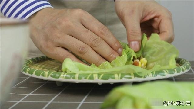 5,首先放上一片包菜叶,在菜帮位置,挖一勺刚刚拌好的饭,把两边的菜叶