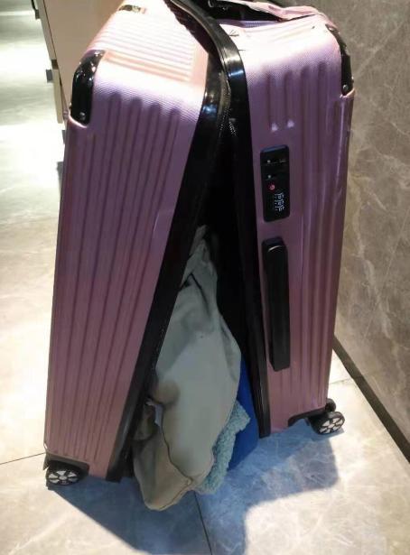 的行李箱,闭合的箱子似乎因为冲击力而摔裂开来,里面的女性衣物也半露