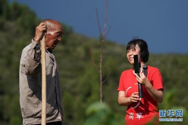 在山西省黎城县岩井村的谷子地里,魏美玲(右)在直播中和一名村民互动