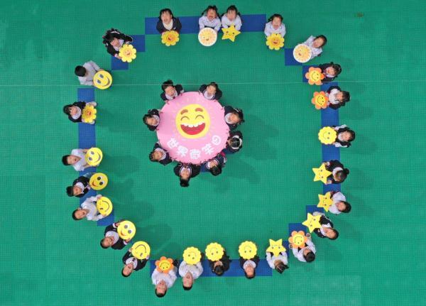 5月8日,浙江省台州市仙居县迎晖幼儿园的孩子们手举笑脸卡做游戏(无人